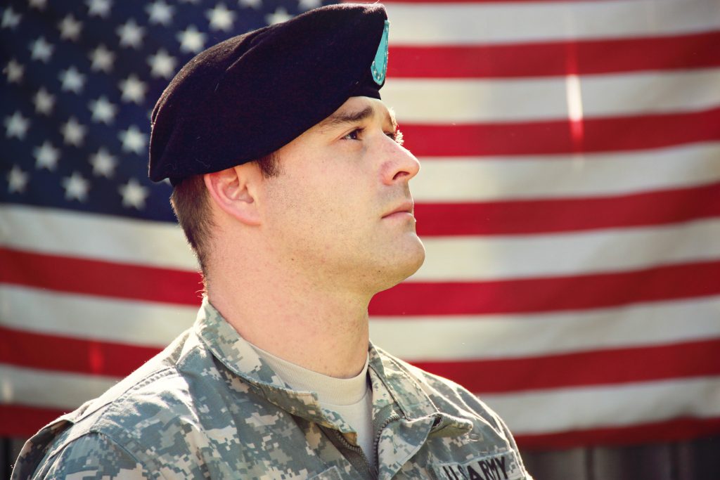 US Army Man with American flag draped behind him